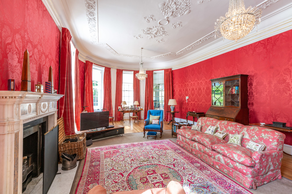 Foto de salón clásico con paredes rojas, suelo de madera en tonos medios, todas las chimeneas y suelo marrón