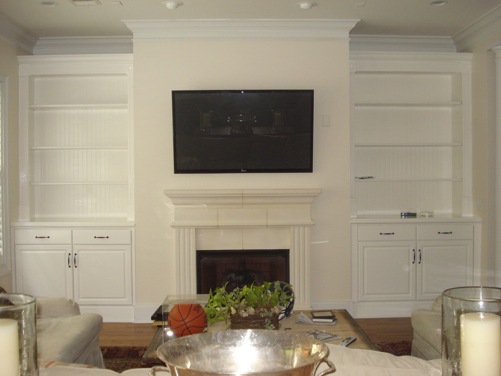 Réalisation d'un salon tradition avec un mur blanc, une cheminée standard et un téléviseur encastré.