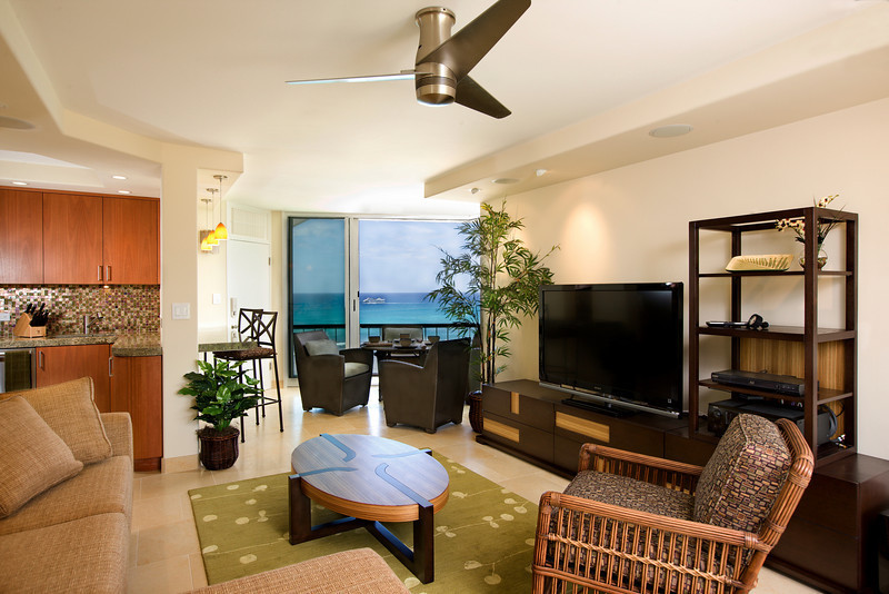 Bild på ett mellanstort tropiskt allrum med öppen planlösning, med beige väggar, kalkstensgolv och en fristående TV