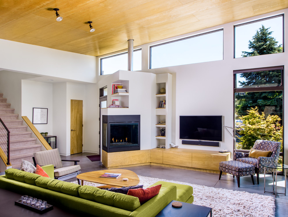 Inspiration for a medium sized contemporary open plan living room in Seattle with white walls, a corner fireplace, a wall mounted tv, concrete flooring and a metal fireplace surround.