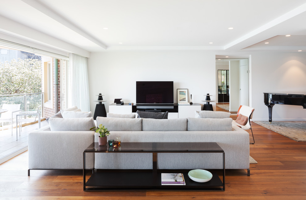 Ispirazione per un soggiorno moderno di medie dimensioni e aperto con pareti bianche, pavimento in legno massello medio, TV autoportante e pavimento marrone