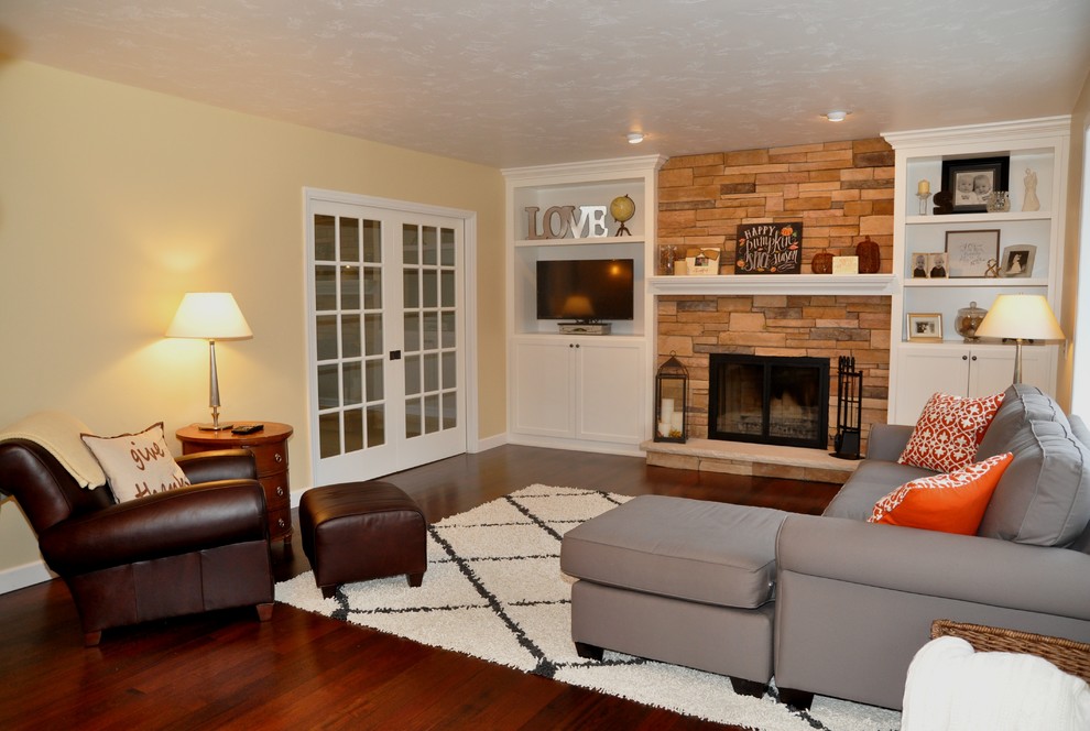 Example of a mid-sized arts and crafts open concept dark wood floor and brown floor living room design in Other with a brick fireplace, a standard fireplace, beige walls and a media wall