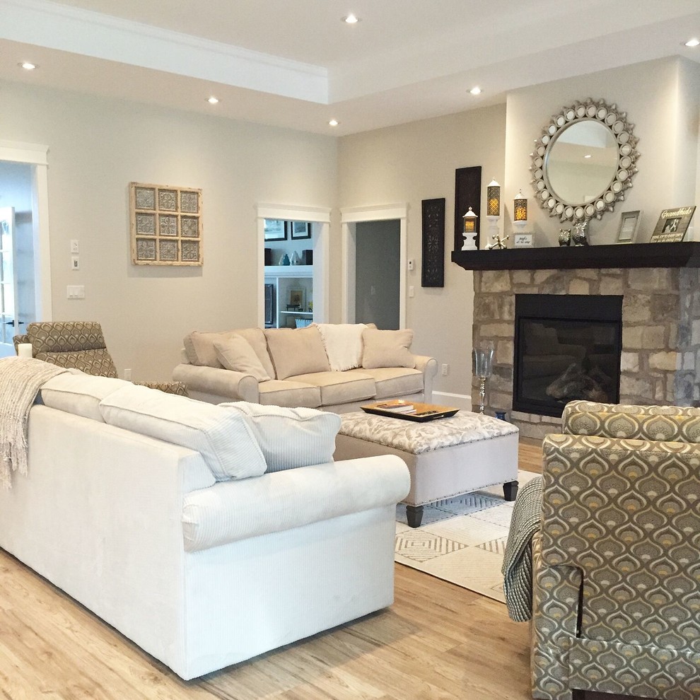 Photo of a large traditional mezzanine living room in Toronto with beige walls, light hardwood flooring, a standard fireplace, a stone fireplace surround and beige floors.