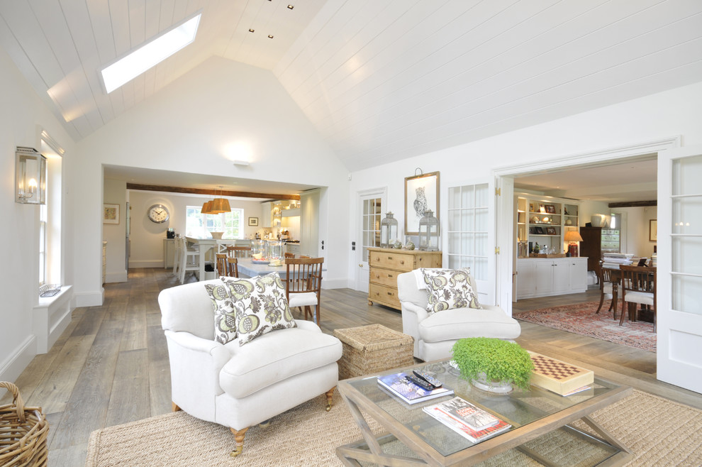 Cette photo montre un grand salon nature ouvert avec un mur blanc et un sol en bois brun.