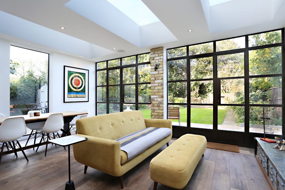 Modelo de salón cerrado contemporáneo de tamaño medio sin chimenea y televisor con paredes blancas, suelo de madera oscura y suelo marrón
