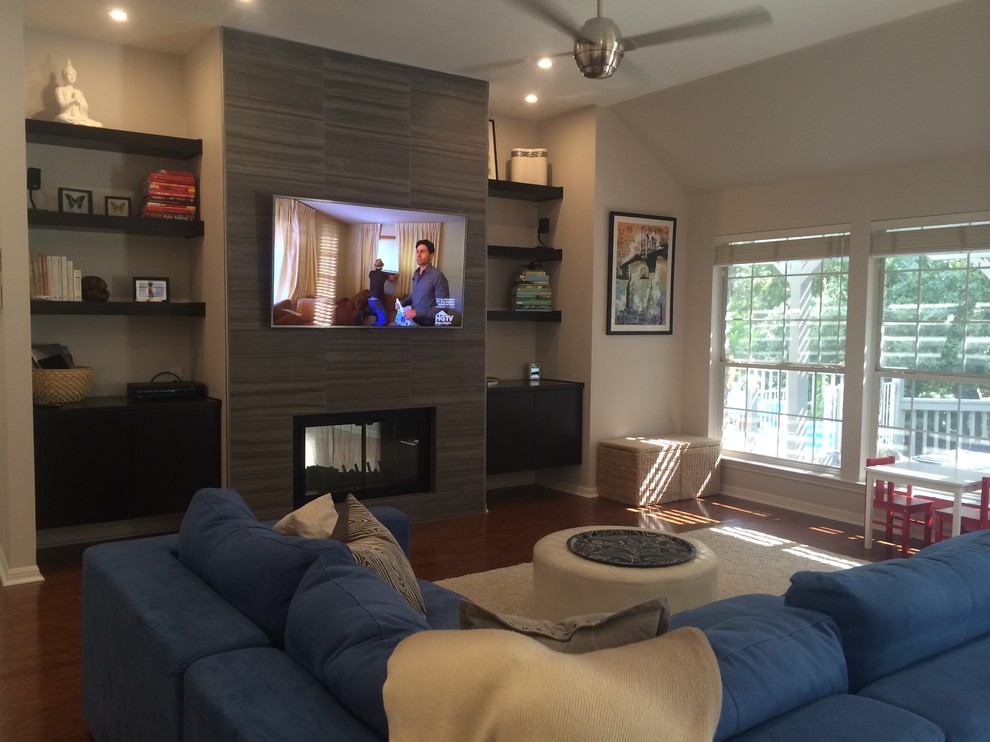 Exempel på ett stort modernt allrum med öppen planlösning, med grå väggar, mellanmörkt trägolv, en dubbelsidig öppen spis, en spiselkrans i trä och en väggmonterad TV