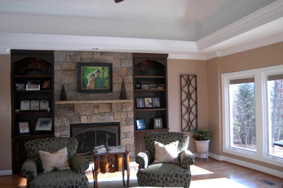 Cette photo montre un salon chic avec un sol en bois brun et un manteau de cheminée en pierre.
