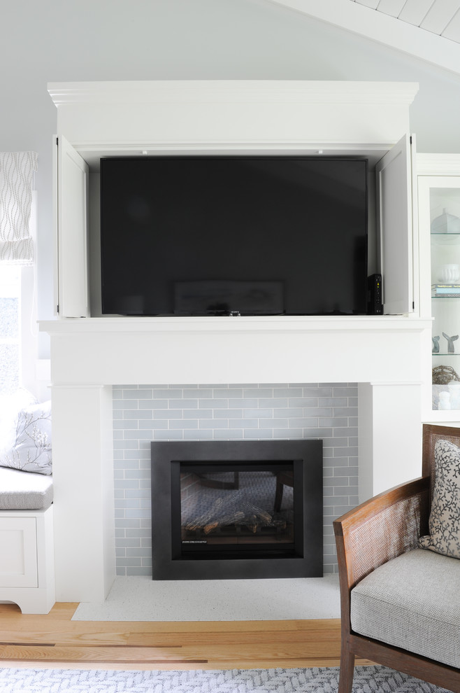 バンクーバーにある高級な小さなビーチスタイルのおしゃれなLDK (グレーの壁、淡色無垢フローリング、標準型暖炉、タイルの暖炉まわり、内蔵型テレビ、茶色い床) の写真