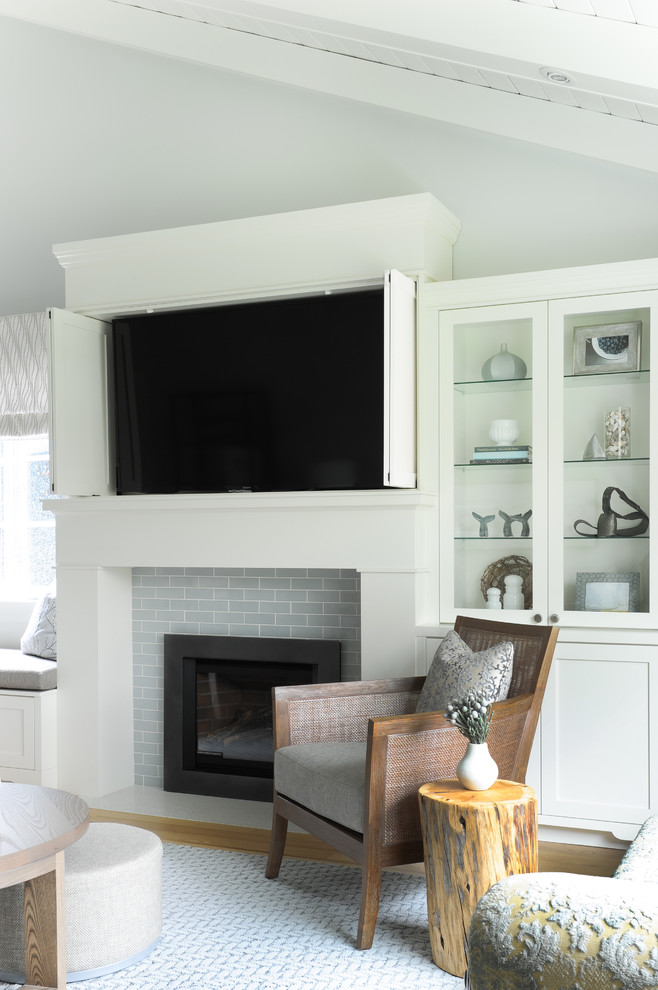 バンクーバーにある高級な小さなビーチスタイルのおしゃれなLDK (グレーの壁、淡色無垢フローリング、標準型暖炉、タイルの暖炉まわり、内蔵型テレビ、茶色い床) の写真
