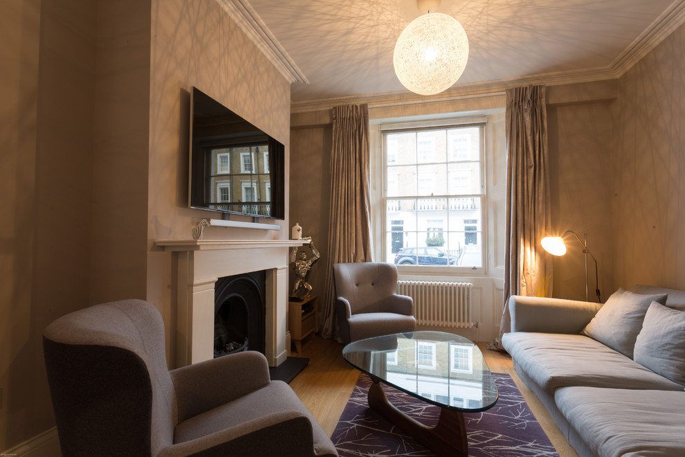 Immagine di un soggiorno tradizionale chiuso con pareti beige, parquet chiaro, camino classico e TV a parete