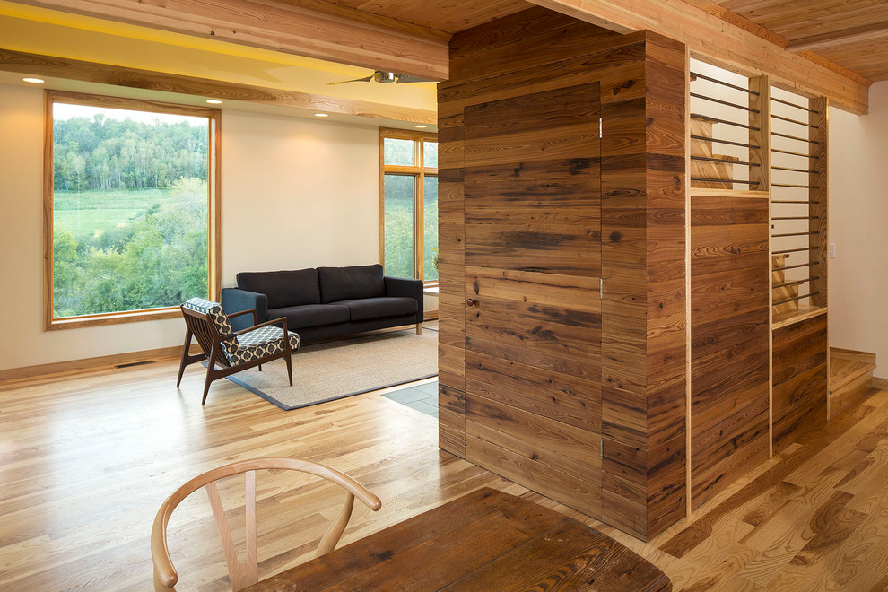 Modelo de salón abierto moderno con paredes beige y suelo de madera en tonos medios