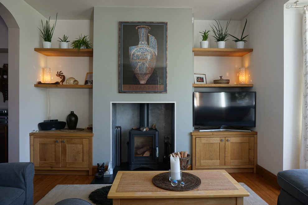 This is an example of a medium sized modern living room in Other with grey walls, light hardwood flooring, a wood burning stove, a freestanding tv and brown floors.