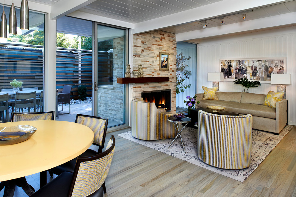 Offenes Retro Wohnzimmer mit weißer Wandfarbe, hellem Holzboden, Kamin und Kaminumrandung aus Stein in Denver