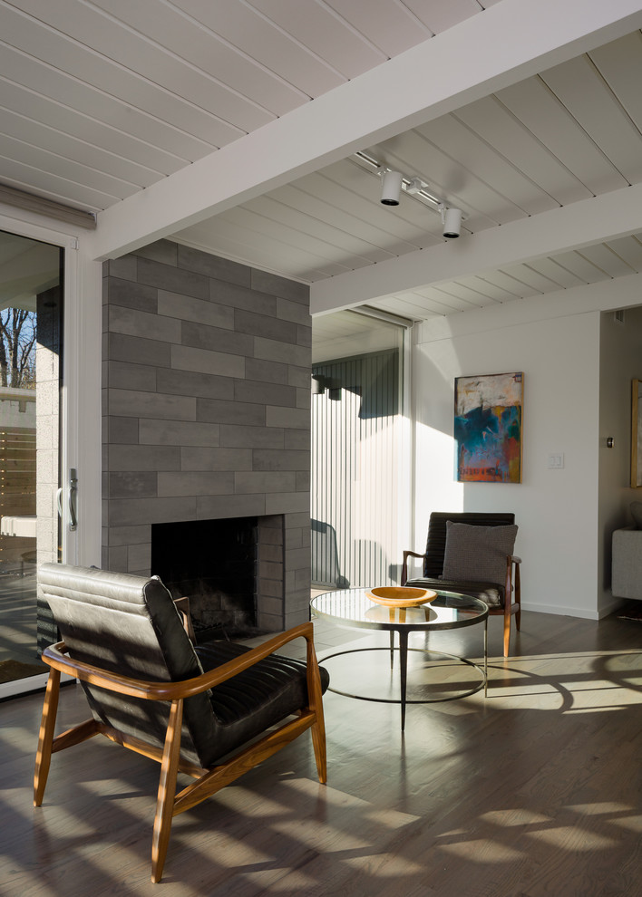 Idée de décoration pour un salon vintage ouvert avec un sol en bois brun, une cheminée standard, un manteau de cheminée en carrelage et éclairage.
