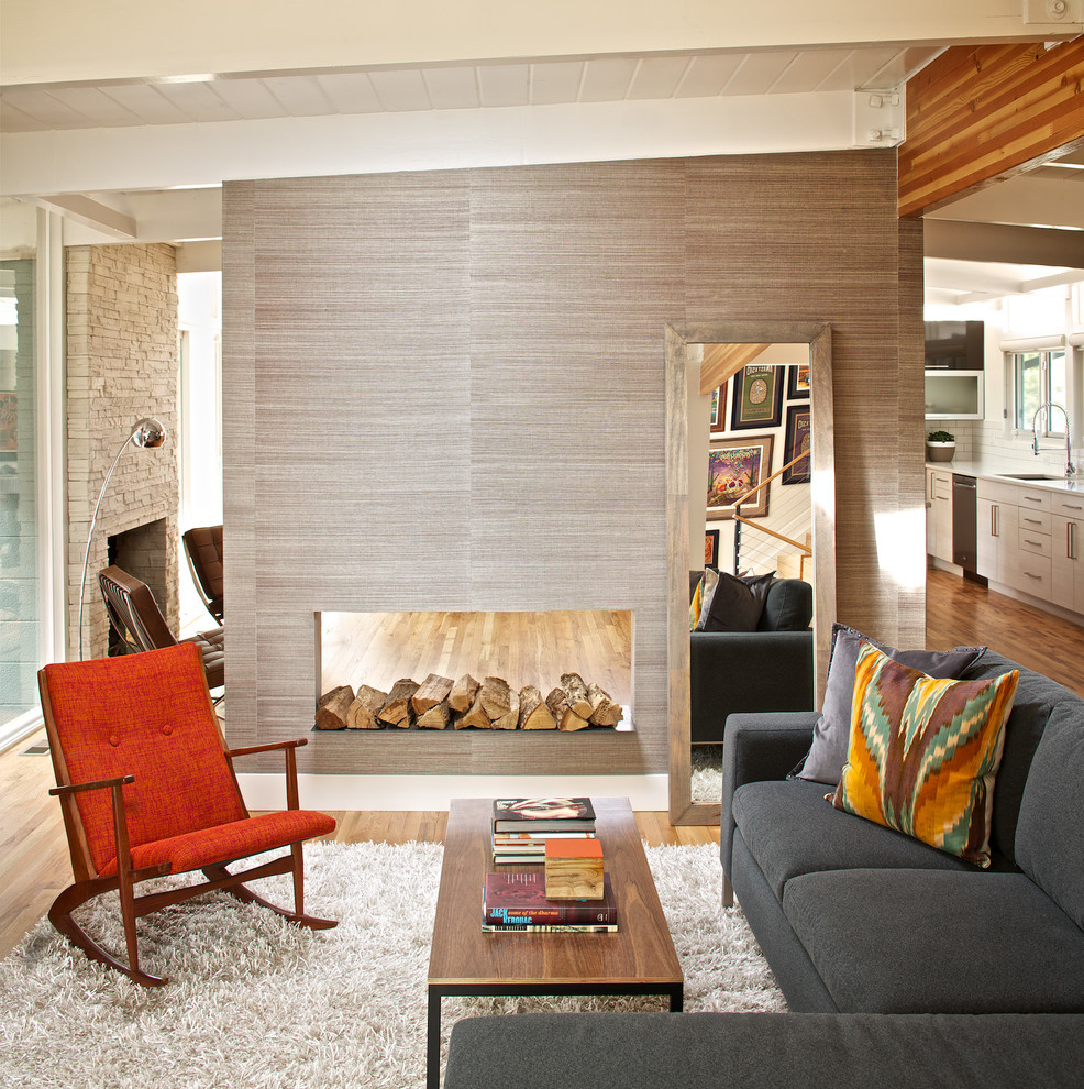 Идея дизайна: парадная, открытая гостиная комната среднего размера в стиле ретро с белыми стенами, паркетным полом среднего тона, двусторонним камином и фасадом камина из дерева без телевизора