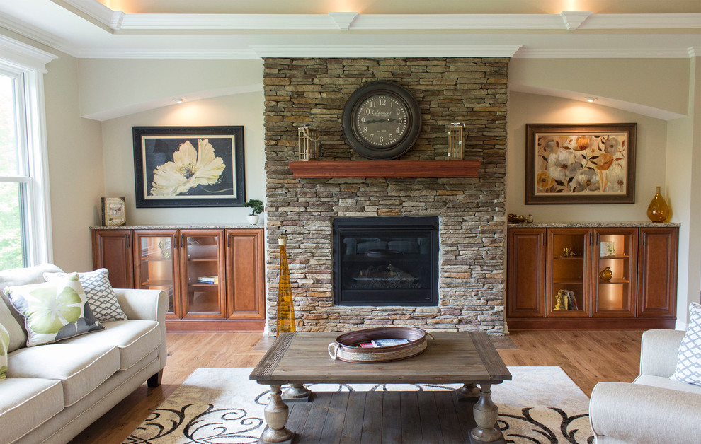 Diseño de salón abierto clásico grande sin televisor con paredes beige, suelo de madera clara y marco de chimenea de piedra