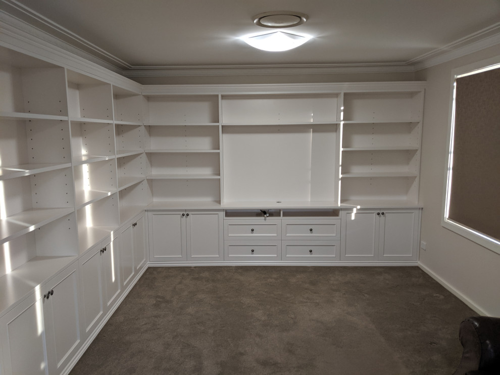 Immagine di un grande soggiorno design chiuso con libreria, pareti bianche, moquette, parete attrezzata e pavimento beige