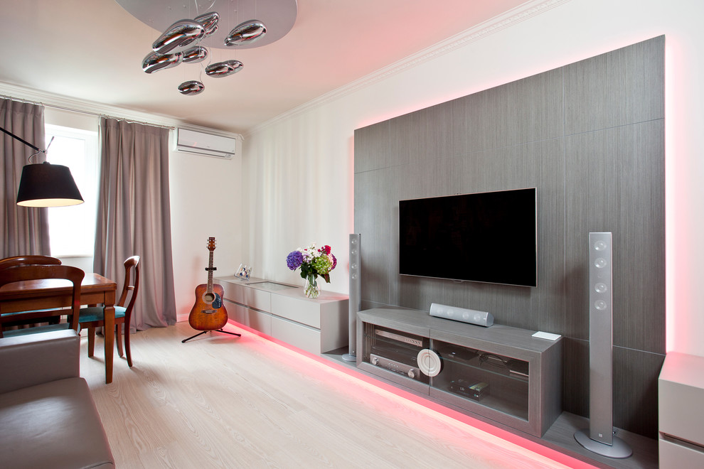 Diseño de salón actual pequeño con paredes grises, suelo de madera clara y televisor colgado en la pared