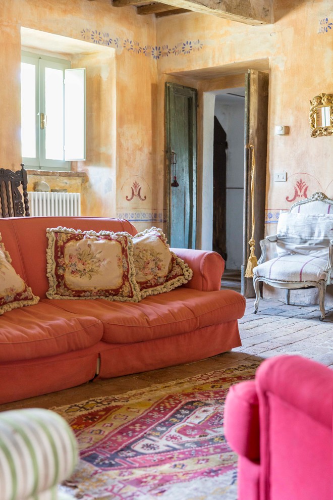 Esempio di un piccolo soggiorno mediterraneo aperto con pareti arancioni, pavimento in mattoni e pavimento beige