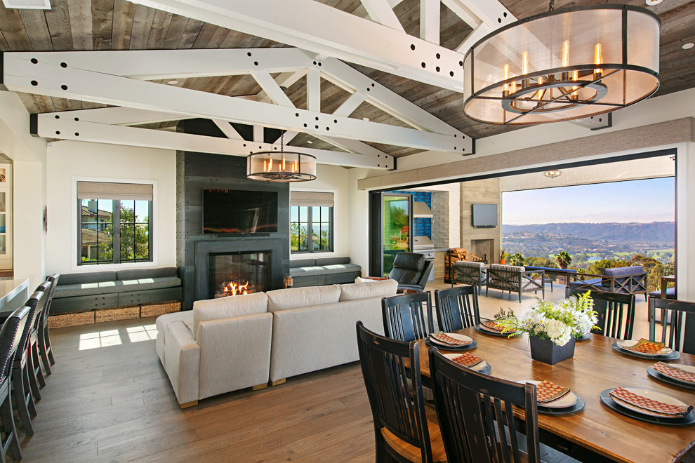 Photo of a farmhouse open plan living room in San Diego with white walls, medium hardwood flooring, a standard fireplace and brown floors.