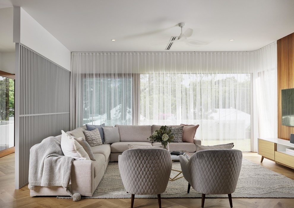 Idée de décoration pour un salon design ouvert avec un mur blanc, un sol en bois brun, un téléviseur fixé au mur et un sol beige.
