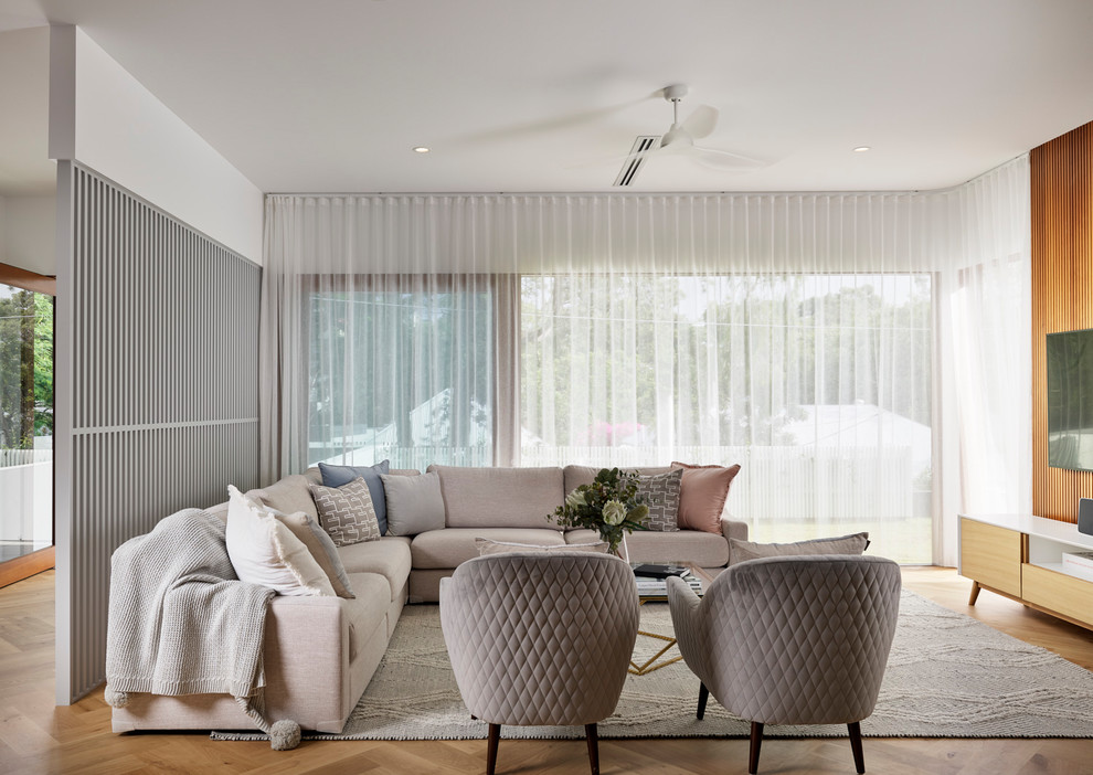 Esempio di un soggiorno design aperto con pareti bianche, pavimento in legno massello medio, TV a parete e pavimento marrone