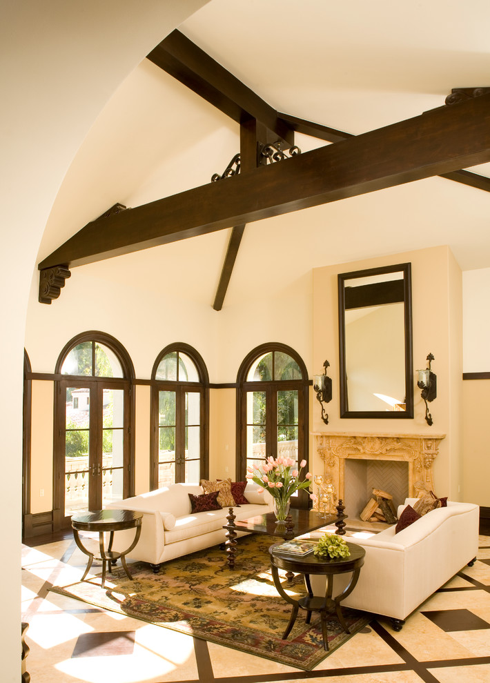 Идея дизайна: гостиная комната в средиземноморском стиле с бежевыми стенами, стандартным камином и ковром на полу