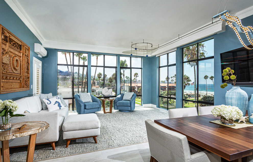 Ejemplo de salón abierto marinero con paredes azules, televisor colgado en la pared y suelo gris