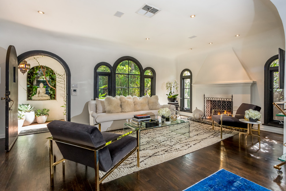 Abgetrenntes Mediterranes Wohnzimmer mit weißer Wandfarbe, dunklem Holzboden, Kamin und braunem Boden in Los Angeles