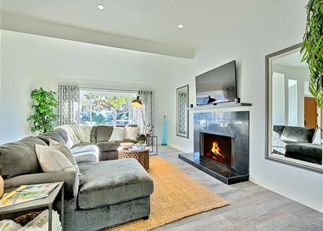 サンディエゴにある低価格の広いビーチスタイルのおしゃれなLDK (白い壁、セラミックタイルの床、標準型暖炉、石材の暖炉まわり、壁掛け型テレビ) の写真