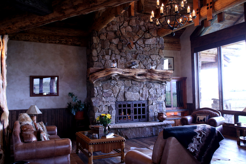 Exemple d'un grand salon montagne ouvert avec une salle de réception, un mur beige, un sol en bois brun, une cheminée standard et un manteau de cheminée en pierre.