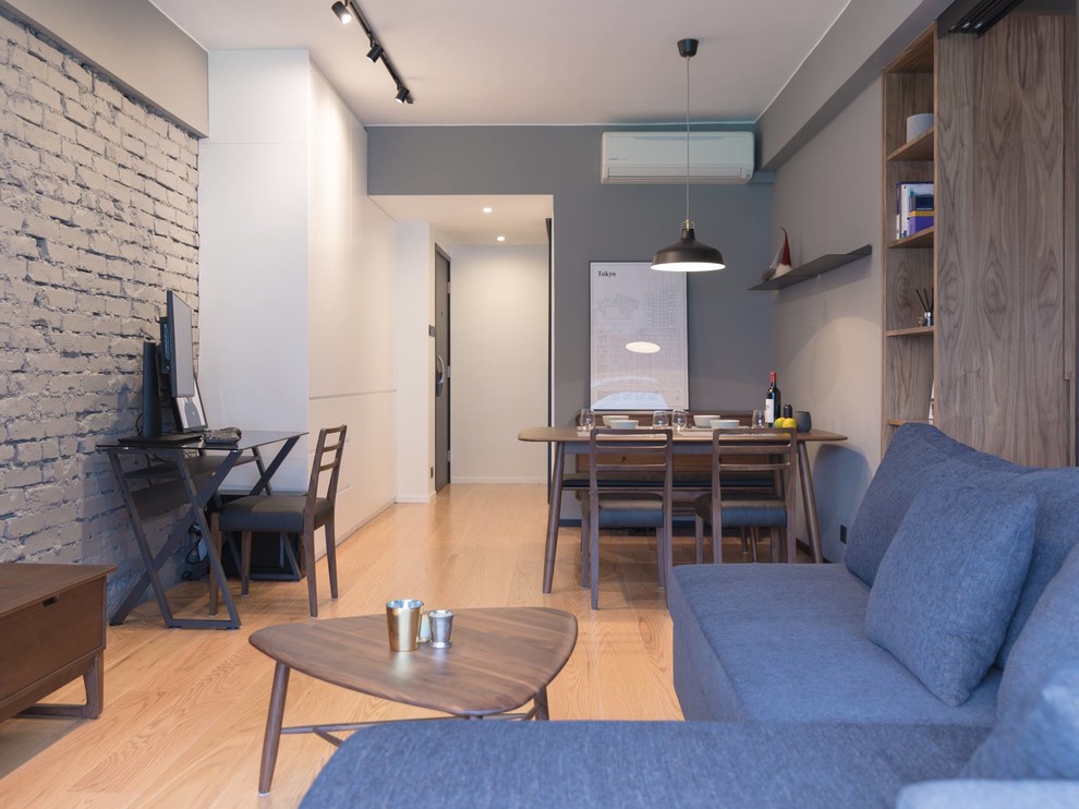 This is an example of a small industrial living room in Hong Kong with grey walls, plywood flooring and a wall mounted tv.