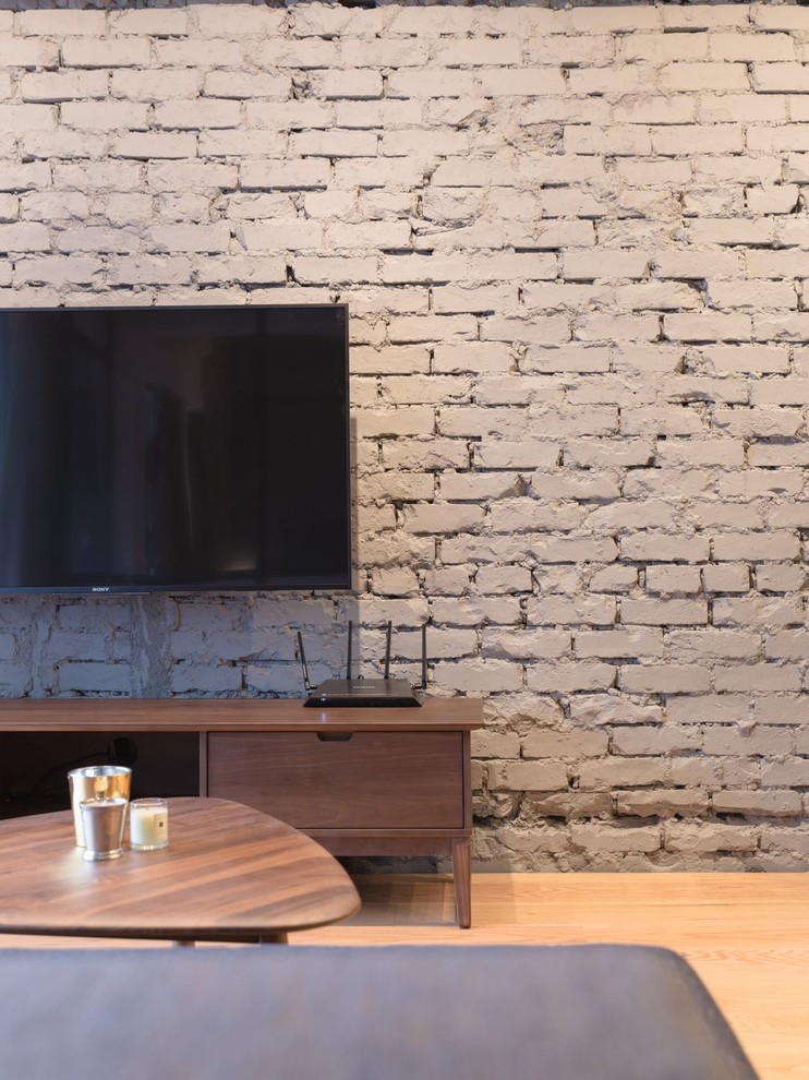 Пример оригинального дизайна: маленькая гостиная комната в стиле лофт с серыми стенами, полом из фанеры и телевизором на стене для на участке и в саду