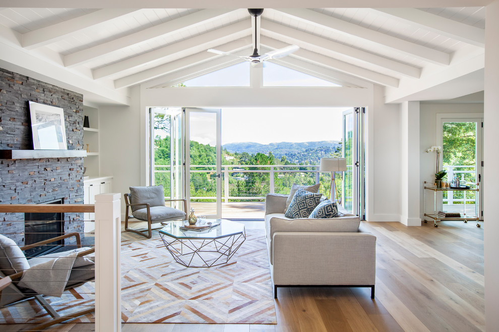 Offenes Klassisches Wohnzimmer mit weißer Wandfarbe, braunem Holzboden, Kamin, Kaminumrandung aus Stein und braunem Boden in San Diego
