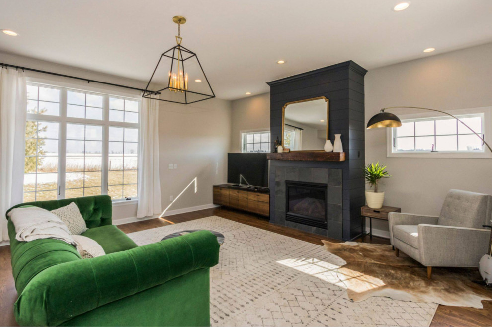 This is an example of a medium sized classic formal open plan living room in Cedar Rapids with white walls, medium hardwood flooring, a standard fireplace, a tiled fireplace surround, a freestanding tv and brown floors.