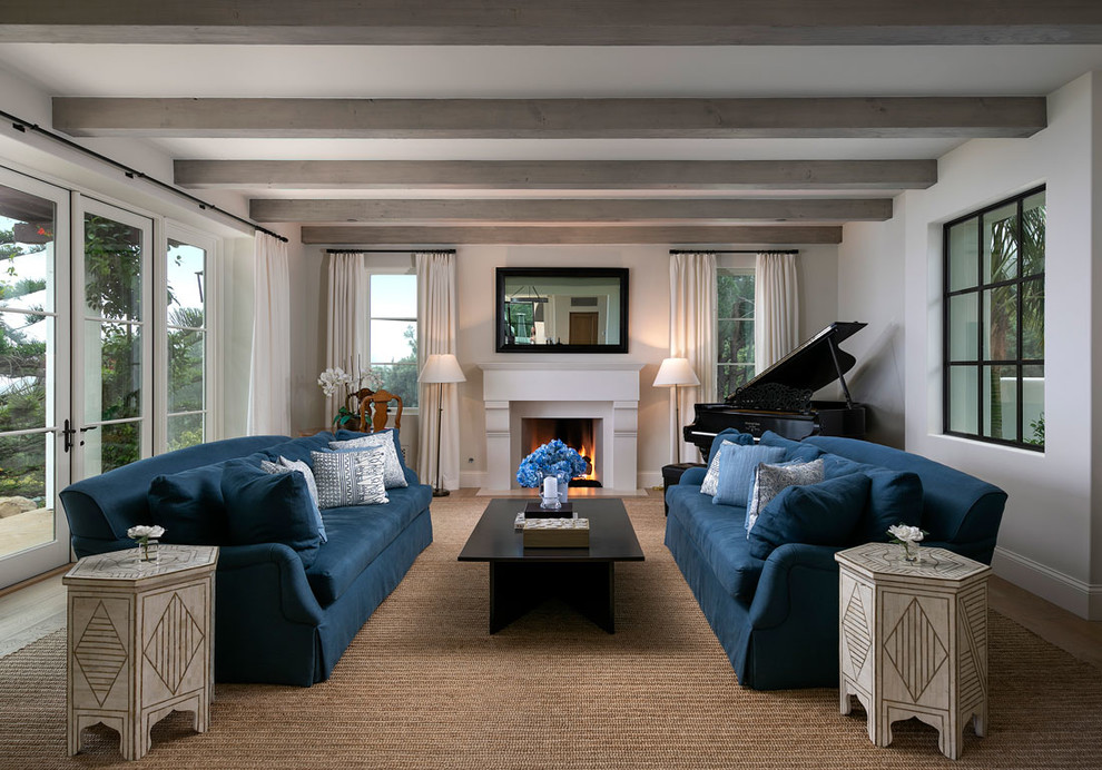 Example of a mid-sized tuscan medium tone wood floor living room design in Santa Barbara with white walls, a standard fireplace, a plaster fireplace, a music area and no tv