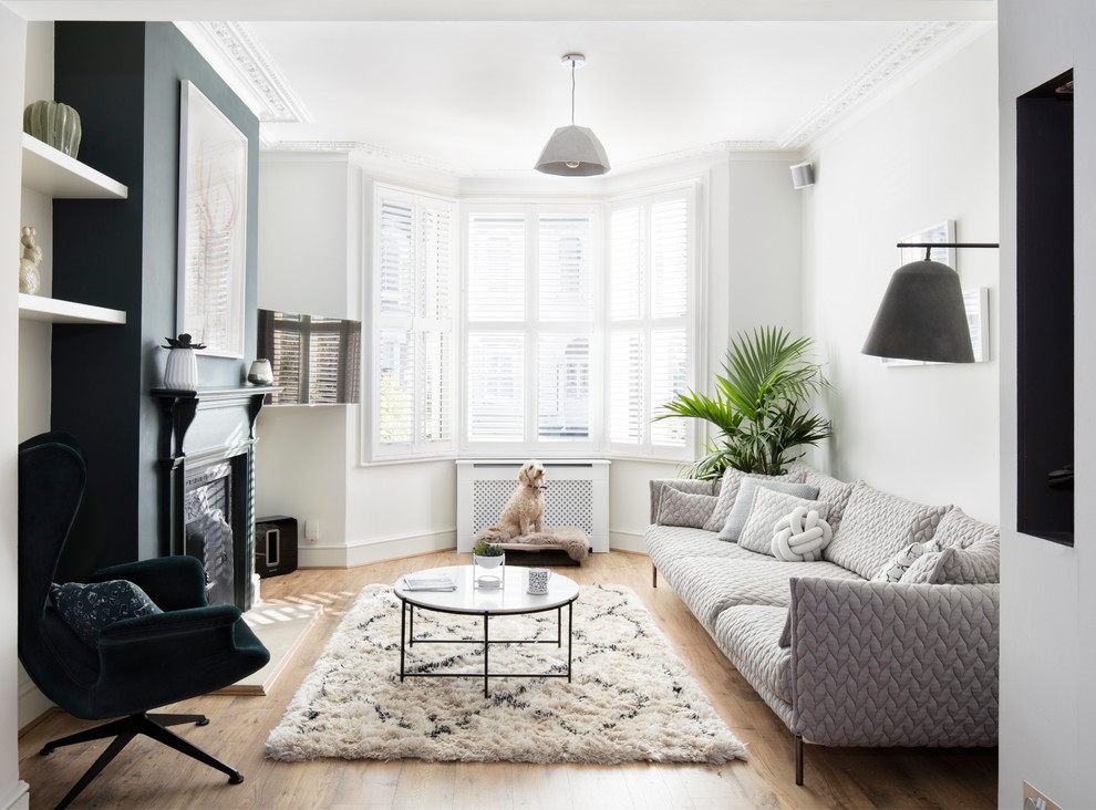 Photo of a medium sized scandi living room in London with white walls, light hardwood flooring, a standard fireplace, a metal fireplace surround, a wall mounted tv and brown floors.