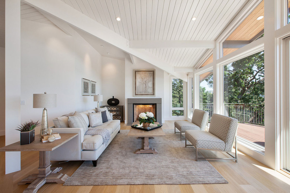 Large classic formal open plan living room in San Francisco with white walls, light hardwood flooring, a standard fireplace, a concrete fireplace surround, no tv and feature lighting.