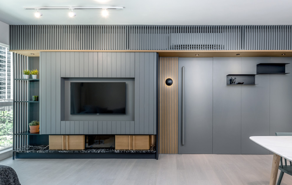 This is an example of a medium sized scandi enclosed living room in Hong Kong with grey walls, light hardwood flooring, a built-in media unit and panelled walls.