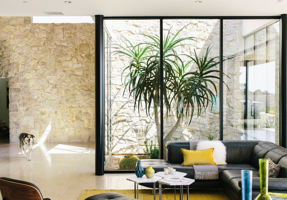 Cette photo montre un salon tendance ouvert avec un sol beige et un mur en pierre.