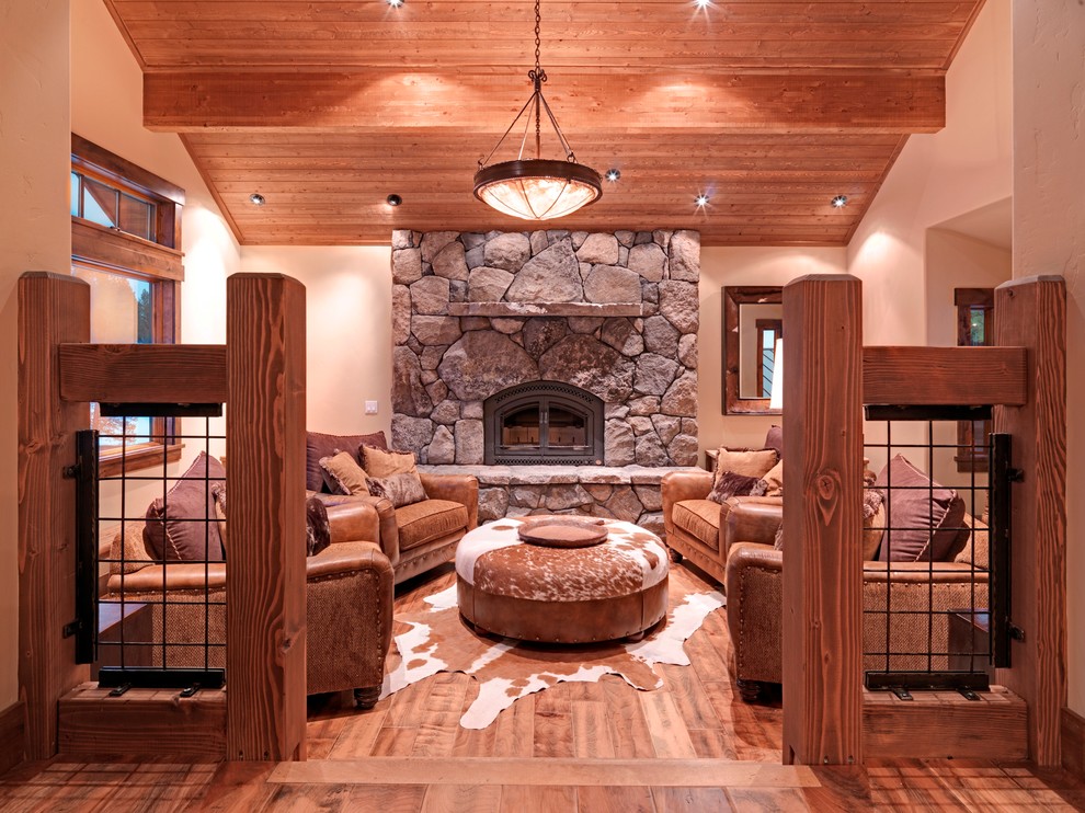 Idées déco pour un salon montagne avec un mur beige, un sol en bois brun, une cheminée standard et un manteau de cheminée en pierre.