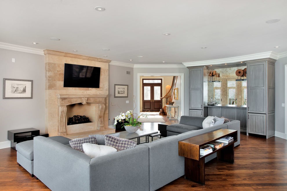 Cette image montre un salon traditionnel de taille moyenne et ouvert avec un mur gris, un sol en bois brun, une cheminée standard, un téléviseur fixé au mur, une salle de réception, un manteau de cheminée en carrelage et un sol marron.