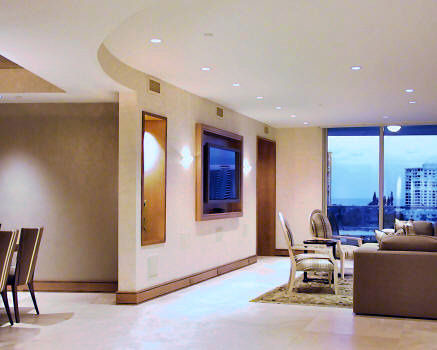 Идея дизайна: огромная открытая гостиная комната в стиле модернизм с бежевыми стенами, полом из известняка и телевизором на стене
