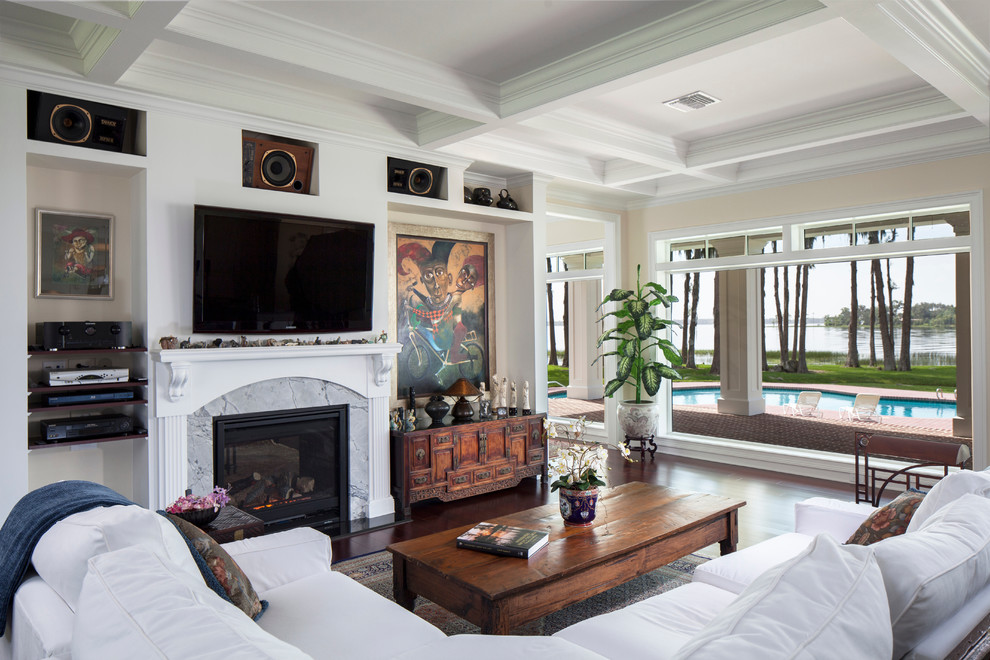 Пример оригинального дизайна: открытая гостиная комната среднего размера в классическом стиле с бежевыми стенами, темным паркетным полом, стандартным камином, фасадом камина из камня, телевизором на стене и ковром на полу
