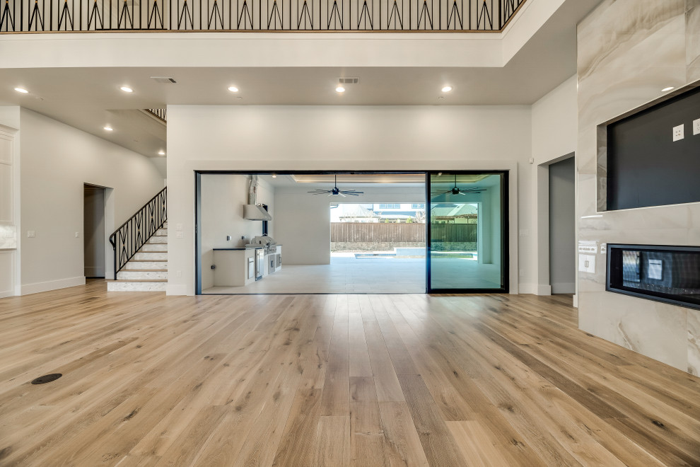 Großes, Offenes Mediterranes Wohnzimmer mit beiger Wandfarbe, braunem Holzboden, Kamin, Multimediawand und beigem Boden in Dallas