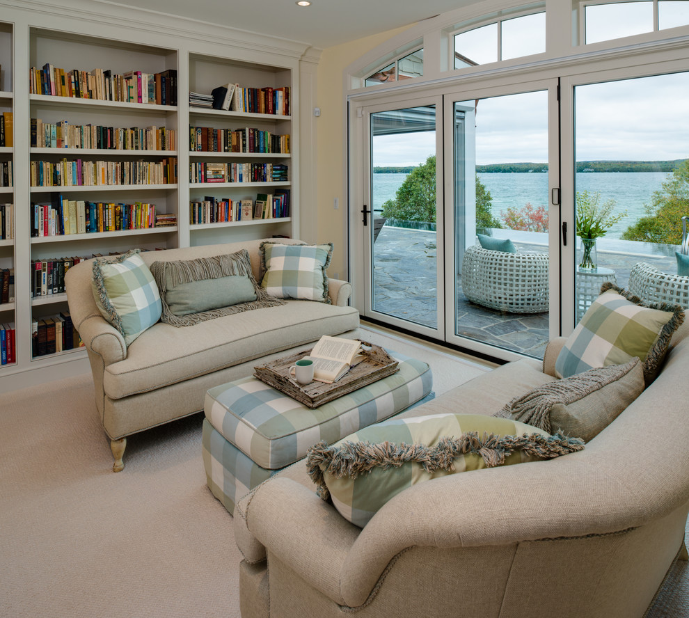 Réalisation d'un grand salon marin ouvert avec une bibliothèque ou un coin lecture, moquette, une cheminée standard, un sol beige et un mur jaune.