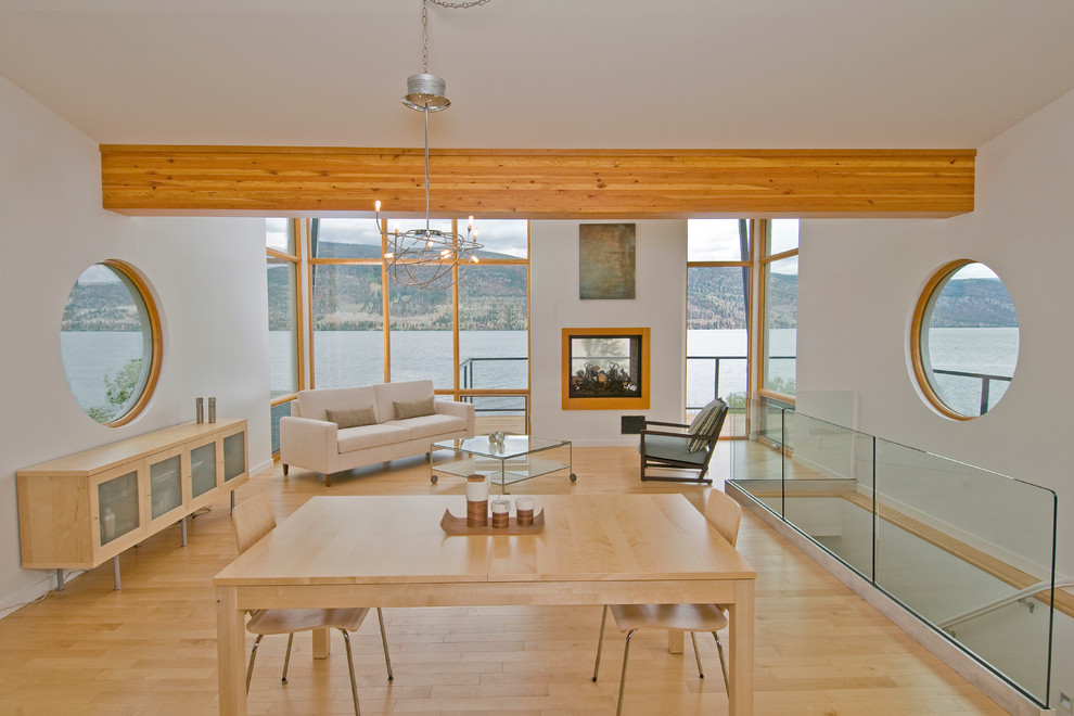Diseño de salón para visitas abierto contemporáneo de tamaño medio con paredes blancas, suelo de madera clara, chimenea de doble cara y marco de chimenea de madera