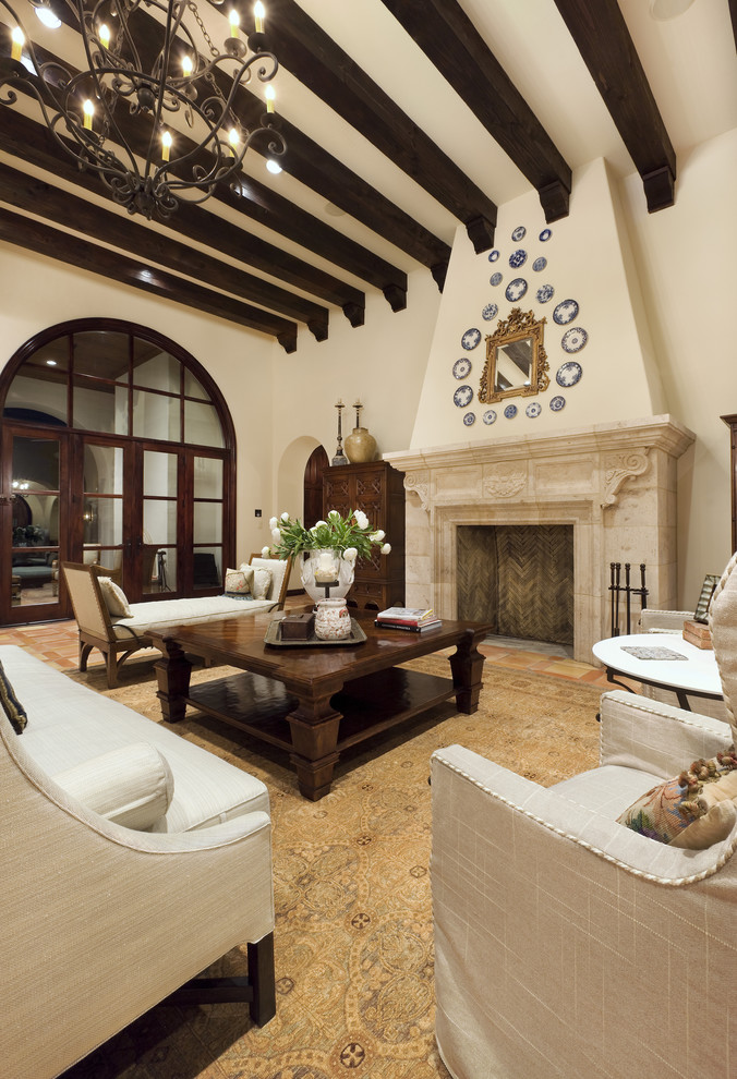 На фото: большая гостиная комната в средиземноморском стиле с бежевыми стенами, стандартным камином и ковром на полу с
