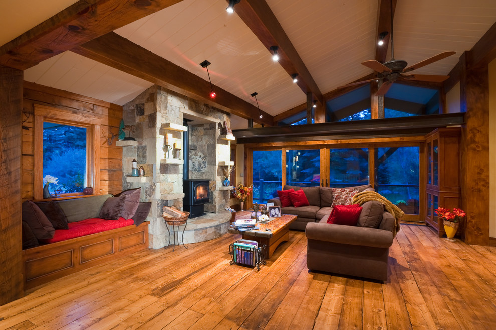 Photo of a medium sized rustic formal open plan living room in Denver with brown walls, medium hardwood flooring, a wood burning stove, a stone fireplace surround, no tv, a vaulted ceiling and wood walls.