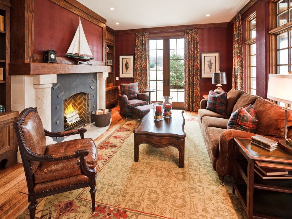 Example of a classic medium tone wood floor living room design in Milwaukee with red walls and a standard fireplace